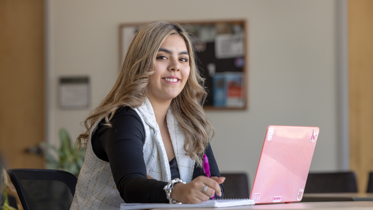 CU Denver BAPA student Stephanie Karr has the option to take all of her classes online. In this photo she sits at a desk with her laptop and a notebook.